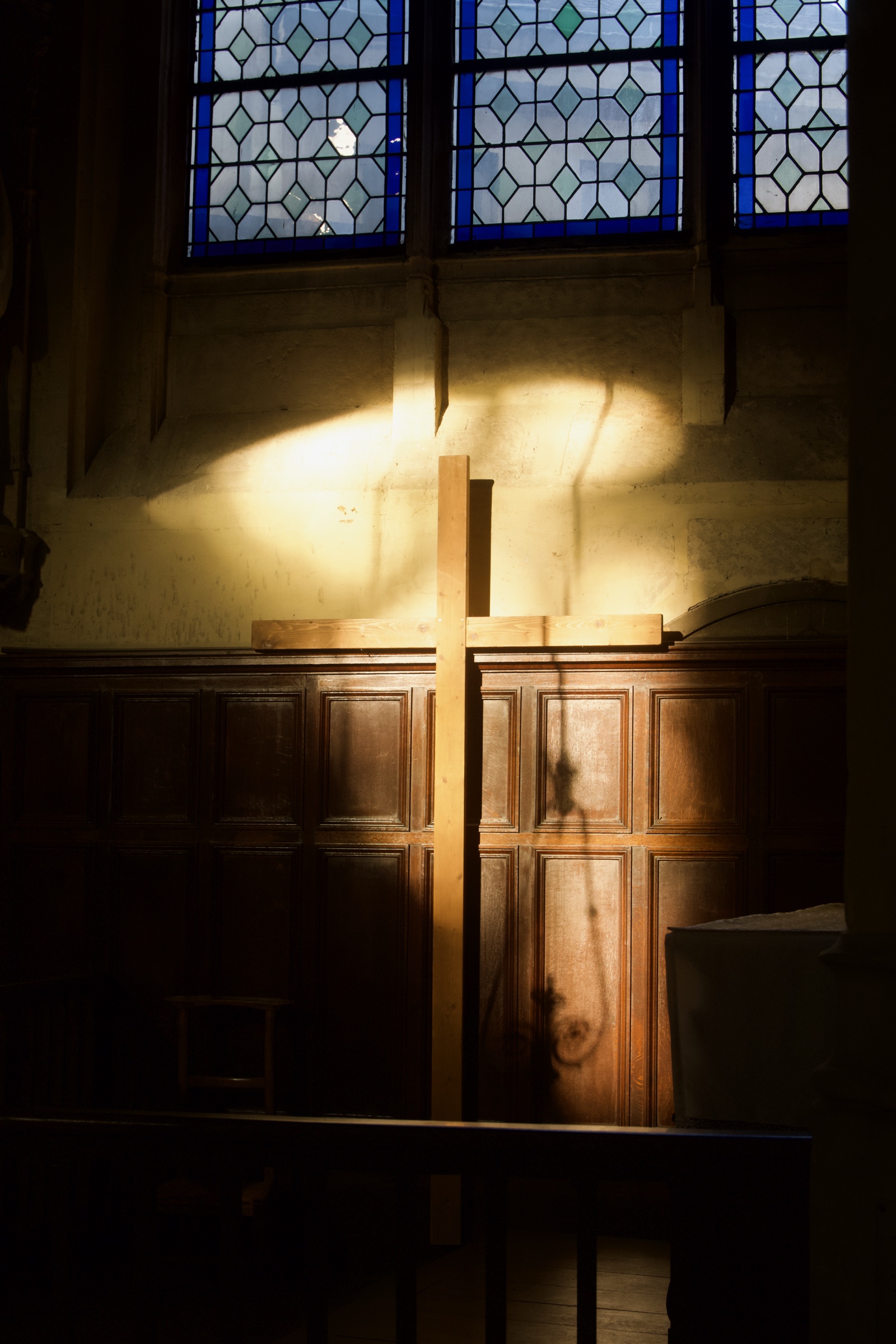 Wooden cross in a pool of window light inside a Paris church