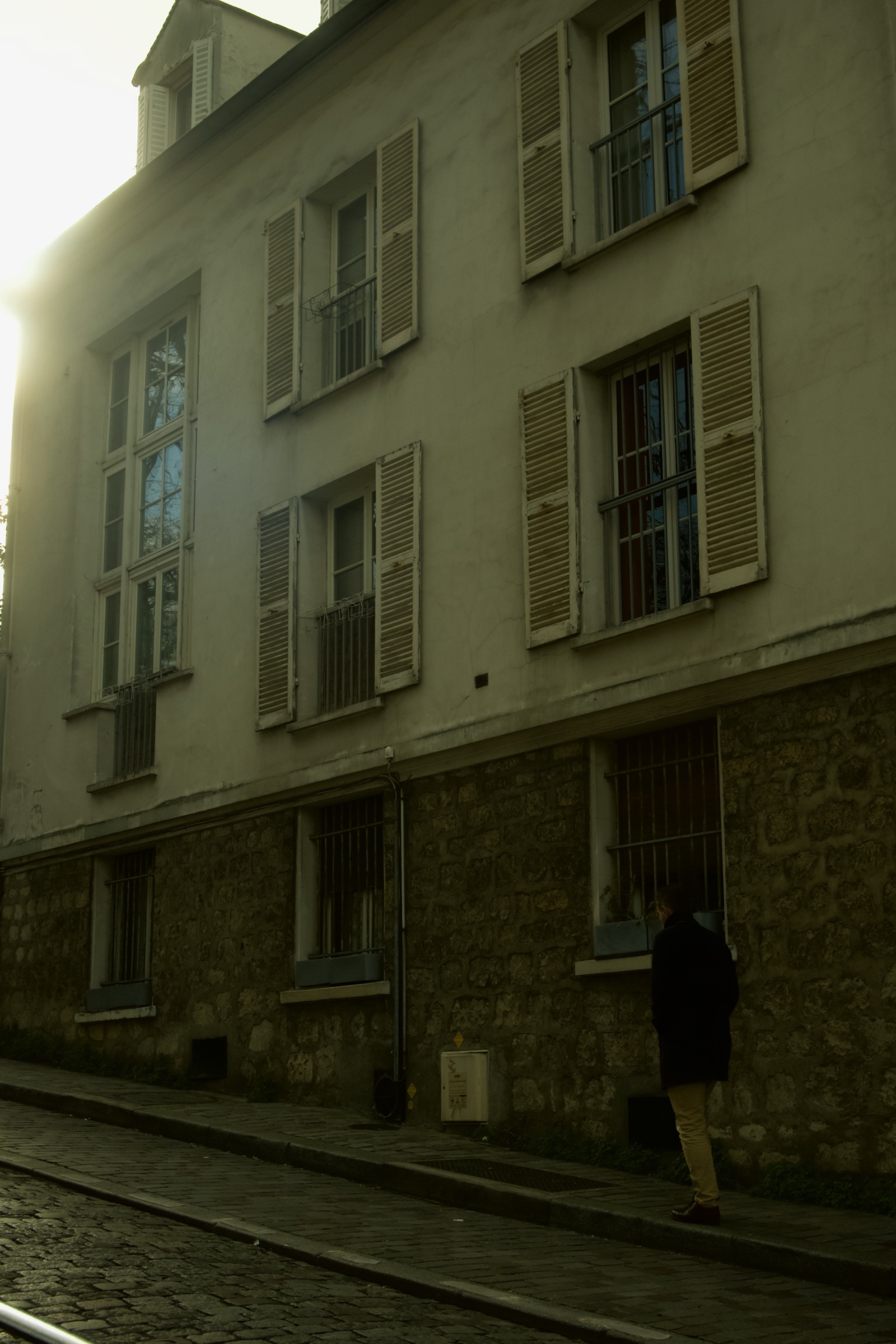 Sunlight over a shuttered building on a cobbled Montmartre street